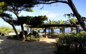 un pavillon avec des arbres et la plage en arrière-plan dans l'établissement Residenza Khaddiuggia, à Pantelleria