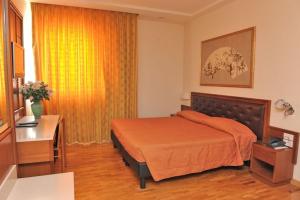 a bedroom with a bed with an orange bedspread at Hotel Svevo in Gioia del Colle