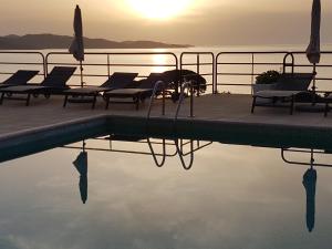 サン・フロランにあるRésidence Costa d'Oruのスイミングプール(椅子付)と水上の夕日を提供しています。