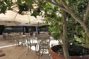 eine Terrasse mit Tischen, Stühlen und einem Baum in der Unterkunft Hotel Svevo in Gioia del Colle