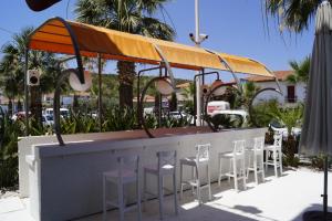 切什梅的住宿－薩赫勒碼頭公寓式酒店，酒吧设有白色的凳子和橙色的天篷