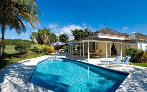 a swimming pool in front of a house at Coconut Grove 1, Luxury Villa by Island Villas in Saint James