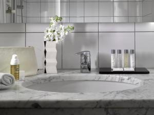 a bathroom counter with a sink and a vase of flowers at K+K Hotel Fenix in Prague