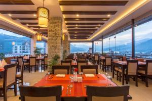 un ristorante con tavoli, sedie e ampie finestre di Bodhi Suites Boutique Hotel and Spa a Pokhara