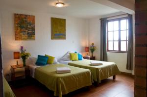 a bedroom with two beds with yellow and blue pillows at Casa de Baraybar in Lima