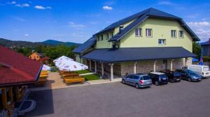 a large yellow house with cars parked in a parking lot at Cubus-Beskidy in Bierna
