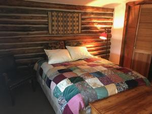 a bed in a room with a wooden wall at La Posada Pintada in Bluff