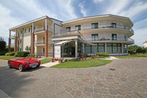 een rode auto geparkeerd voor een gebouw bij Nettuno Residence Hotel in Peschiera del Garda