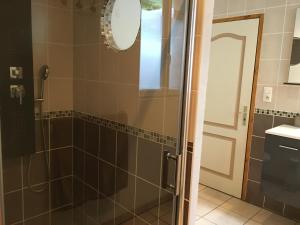 La salle de bains est pourvue d'une douche avec une porte en verre. dans l'établissement Gîte L'Annexe, à Crotenay