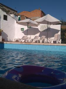 a pool of water with chairs and umbrellas at Casa Rural Tita Sacramento in Hornachos