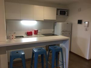 cocina con encimera y 2 taburetes azules en Departamento moderno en Rosario