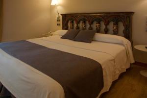 
a white bed sitting in a bedroom next to a wall at Hospederia Chapitel in Estella
