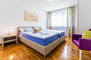 1 dormitorio con 1 cama grande y sillas moradas en Tertianum Residenza Al Lido - Appartements & Restaurant en Locarno