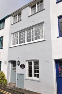 a white building with windows and a blue door at Shipwrights Cottage in Salcombe
