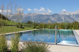 a swimming pool with mountains in the background at Hotel Geisler Tulfes in Tulfes