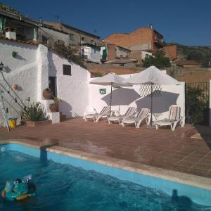 a swimming pool with lounge chairs and a umbrella at Casa Rural Tita Sacramento in Hornachos
