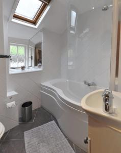 Baño blanco con bañera y lavamanos en Shipwrights Cottage, en Salcombe