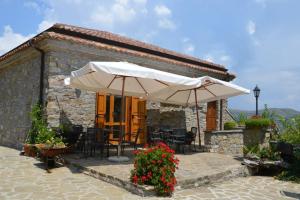 un patio con mesas y sombrillas frente a un edificio en Dormire al Casale, en San Mauro Cilento