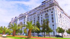 a large white building with palm trees in front of it at Beautiful House By the sea in Batumi