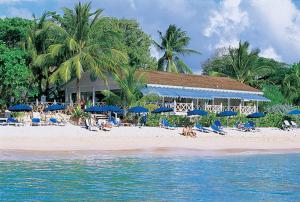 a beach with blue umbrellas and people sitting on the beach at Coconut Grove 8 Luxury Villa by Island Villas in Saint James