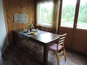 a wooden table and chair in a room with windows at Mosina Vesiveski in Vissi