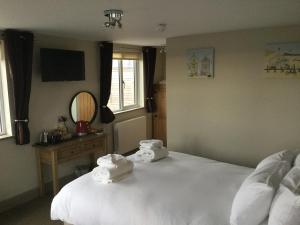 a bedroom with a white bed with towels on it at The Sail Loft in Southwold