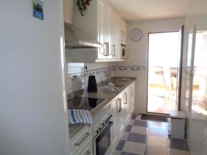 カルプにあるEdificio Playa De Oroのタイルフロアのキッチン(白いキャビネット付)