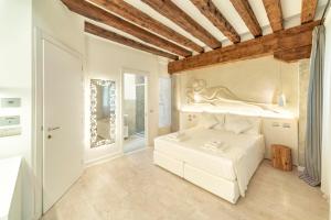 a bedroom with a white bed with a statue on the wall at Ca' de la Fonte - WENICE Deep Culture in Venice