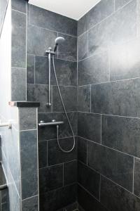 ein Bad mit einer Dusche mit schwarzen Fliesen in der Unterkunft Best Western Plus Amsterdam Airport Hotel in Hoofddorp