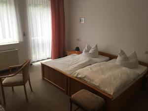 a bedroom with a bed with a chair and a window at Landhaus Pension Lützen-Stadt in Lützen