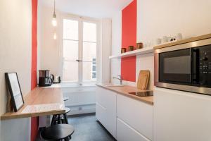 een keuken met witte kasten, een magnetron en een raam bij Honorê - Suite Trois Maries in Lyon