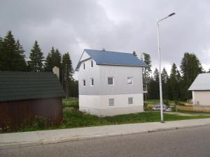 a white house with a blue roof on the side of a street at Apartman Lucija in Žabljak