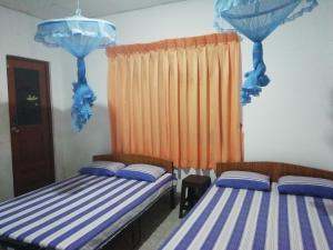 2 Betten in einem blau-weißen Zimmer in der Unterkunft Didula Holiday Resort in Anuradhapura