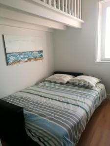 a bed in a bedroom with a painting on the wall at Boulevard de la Mer 33 Apartam 11 in Hendaye