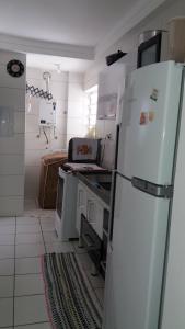La cuisine est équipée d'un réfrigérateur blanc et d'un four. dans l'établissement Condominio Port. da cidade Aracaju, à Aracaju