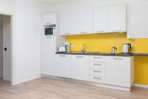 a kitchen with white cabinets and a yellow wall at Casa Carla in Nago-Torbole