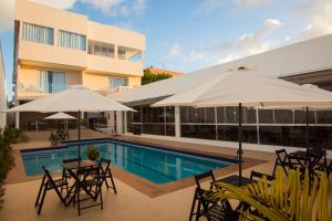 a swimming pool with tables and umbrellas next to a building at ROYAL Hotel & Gastronomia in Macapá