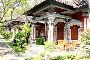 ein Haus mit einer Veranda und Stühlen davor in der Unterkunft Hotel Shri Ganesh in Lovina