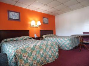 Habitación de hotel con 2 camas y paredes de color naranja en Tazewell Motel, en Tazewell