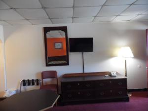 Habitación con escritorio y TV en la pared. en Tazewell Motel, en Tazewell