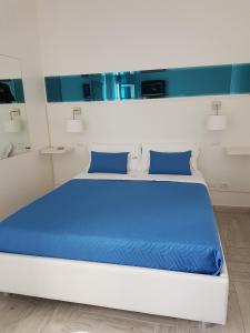 uma cama branca com almofadas azuis num quarto em Di Ma B&B em Porto Cesareo