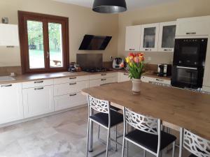 a kitchen with a wooden table with chairs and a vase of flowers at Maison 6 chambres au cœur du circuit des 24h du Mans in Mulsanne