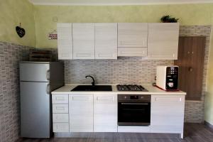 una cucina con armadi bianchi, lavandino e frigorifero di Mary's House a Civitavecchia