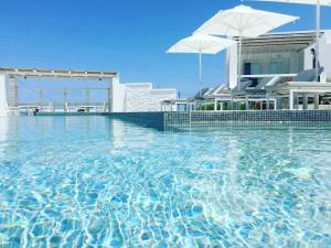 a pool of water with two white umbrellas in it at Lemon Tree Houses in Áno Meriá