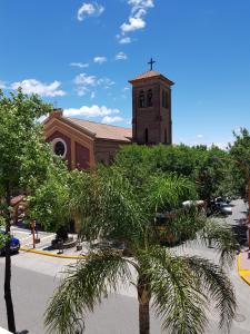 una iglesia con una palmera frente a un edificio en Departamento Loft VCP en Villa Carlos Paz