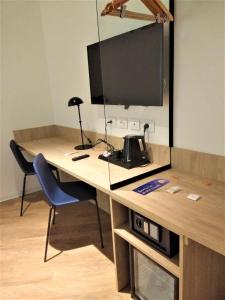 a desk with a television and a blue chair at Air Rooms Rome Airport by HelloSky in Fiumicino