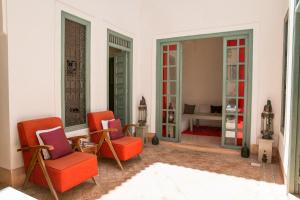 sala de estar con 2 sillas de color naranja y sofá en Riad Dar Aicha en Exclusivité, en Marrakech