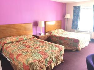 2 camas en una habitación de hotel con paredes púrpuras en Scottish Inns Albany, en Albany