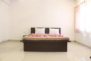 a bedroom with a bed with red and white pillows at Malhar Bungalow in Panchgani +62 photos