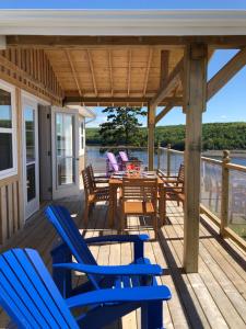 una terraza con sillas azules, mesa y sillas en Still Point Lodge, en Deep Brook